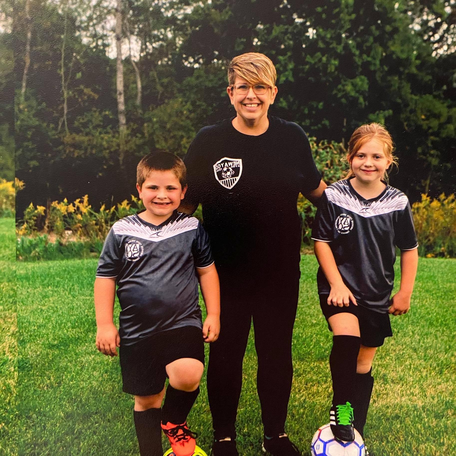 Erica Herwig standing with her two children in their soccer jerseys